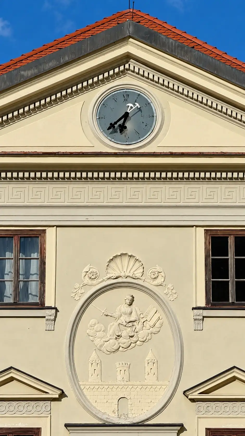 Top to bottom: gabled roof; triangular pediment; tympanum with clock; crowning cornice; Justitia relief with town fortifications