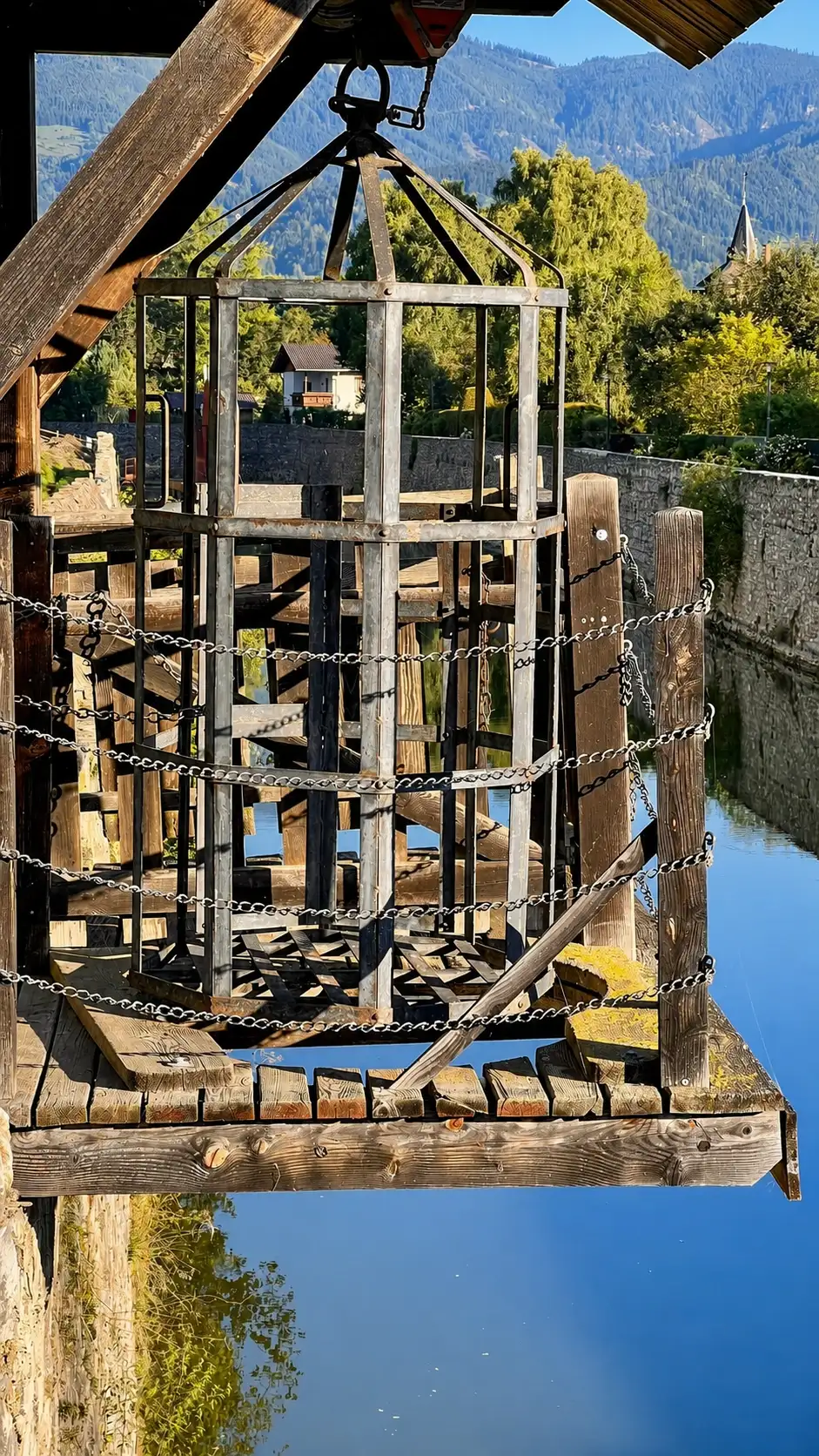 The wooden platform below the cage has a "dunking hole". The metallic cage was lowered through the hole to dunk the cheating baker into the moat.