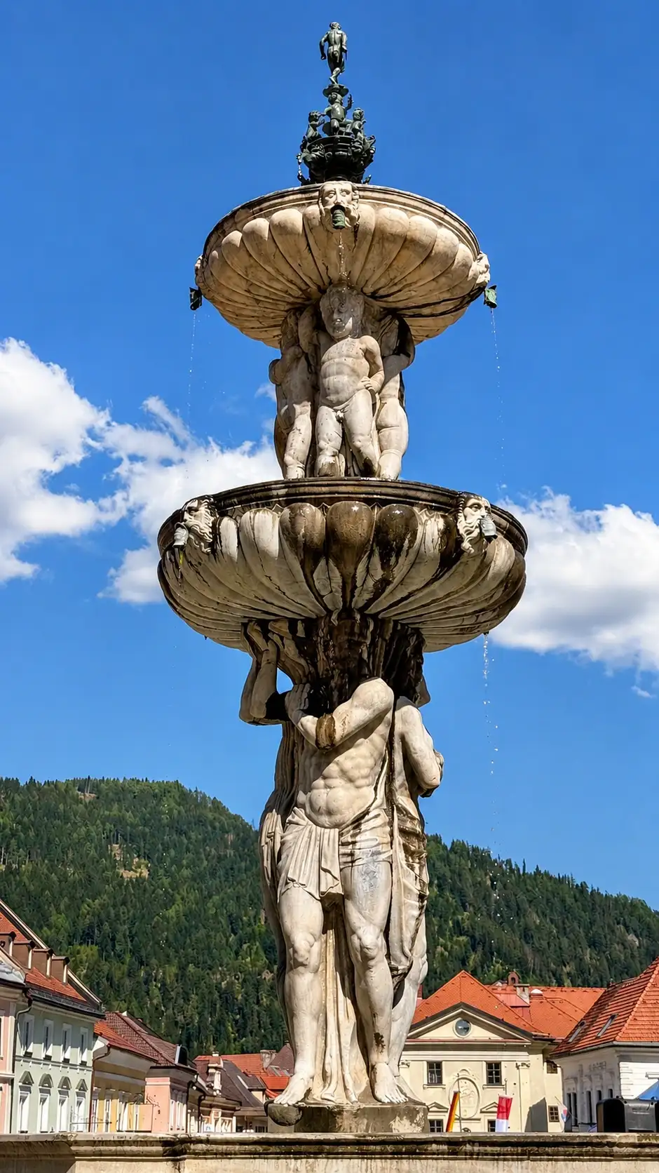 Three tritons hold the larger fountain bowl. Four putti-like figures hold the smaller fountain bowl.
